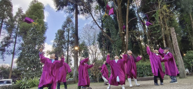 GLC Shillong students celebrating outdoors in purple gowns